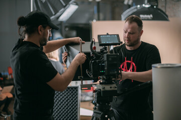 Director of photography with a camera in his hands on the set. Professional videographer at work on filming a movie, commercial or TV series. Filming process indoors, studio