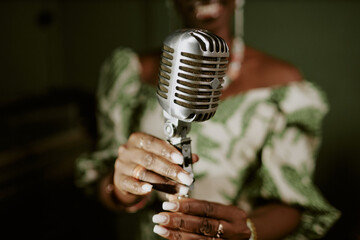 Unrecognizable Black female singers hands adjusting microphone for performance, closeup shot