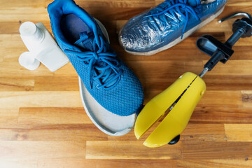 blue used running shoe , sole peeled back and damaged on wood desk waiting for repair