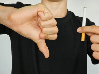 Man boy teenager shows thumb down cigarette