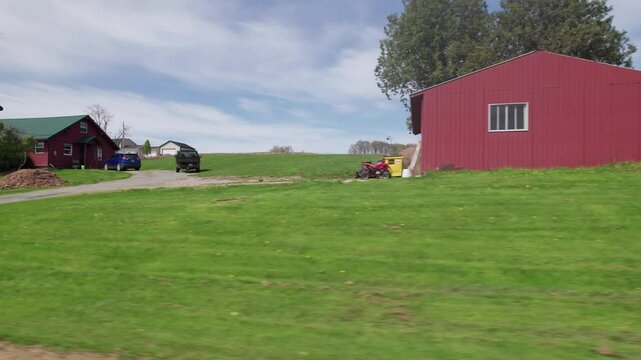 Driving around small town America in Ohio countryside, moving past wood buildings, old barns, farm land, crops, trees, and large fields in conservative rural area outside Columbus and Danville, OH 