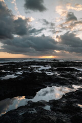 Obraz premium Sunset on the coast of Bajamar with clear skies and clouds with mirrored puddles.