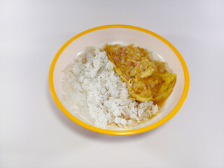Soupy sour omelette cooked in tamarind sour sauce, served alongside rice on a plate with a yellow accent against a white background, creating a vibrant and tangy culinary presentation