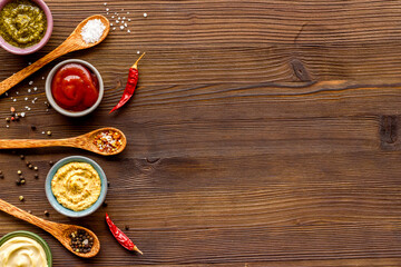Many different sauces in bowls and spices in spoons, top view. Food or cooking background