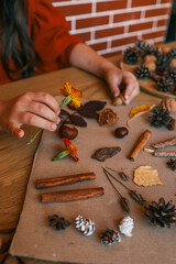 A child makes a herbarium in an album from autumn colorful red, yellow and brown leaves. Happy autumn time