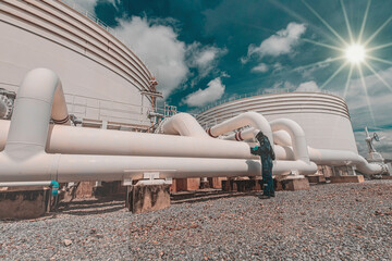 Male worker inspection at steel long pipes and pipe elbow in station oil factory during refinery...