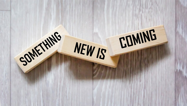 Something new is coming symbol. Wooden blocks with the words Something new is coming. Beautiful gray background. Concept of business and something new. Copy space.