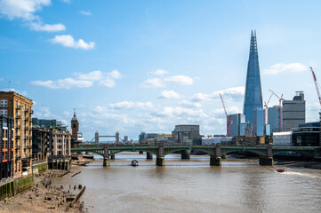 Low tide on the River Thames against the City of London and skyline in summer, England