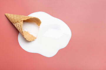 Melted ice cream and wafer cone on pale pink background, top view. Space for text
