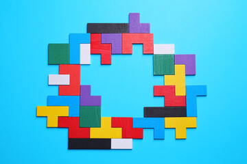 Colorful wooden puzzle pieces on light blue background, top view