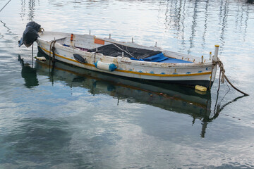 Small traditional colorful fisherman boat in the tranquil water of the port of Syracuse, Sicily, Italy
