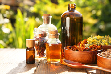 Different tinctures and ingredients on wooden table outdoors