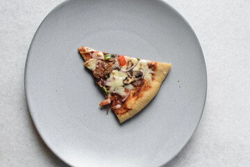 Overhead view of chicken pizza slices on a grey plate, top view of beef and mushroom pizza slice