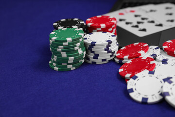 Poker chips and playing cards on blue table, closeup. Online game