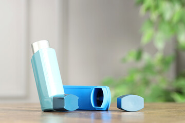 Inhalers on wooden table indoors, closeup with space for text. Asthma treatment