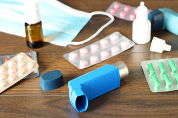 Different asthma medications on wooden table indoors, closeup