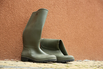 Grey rubber boots on pavement near wall outdoors