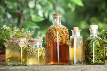 Different natural tinctures on wooden table outdoors, closeup