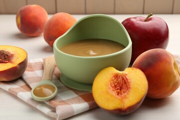 Delicious baby food in bowl and fresh ingredients on white wooden table