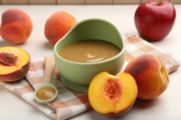Delicious baby food in bowl and fresh ingredients on white wooden table