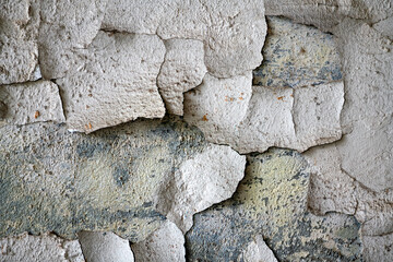 Various old layers of wall paint on the facade of an industrial ruin. Flaking paint residue, dirt and dust form a rough, uneven surface in shades of white and gray. Lost-place background