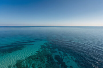 a aerial view photo of a calm, crystal-clear ocean with subtle gradients of blue, creating a serene and minimalist background