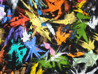 Various multi-colored spots of different shapes from paint brushes with gouache and acrylic paint on black fabric, abstract background