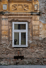 The distressed surface of the old building’s exterior with an antique window