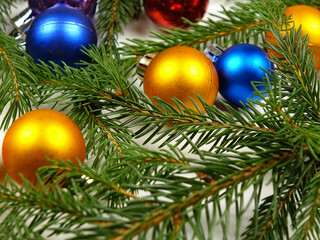 Multicolored Christmas glass balls lay out on fresh green fir branches on a white background. Christmas festive composition, background