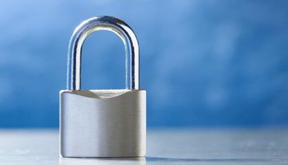 Fototapeta premium Stainless steel padlock on metal surface. Blurred backdrop.