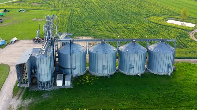 Aerial view agro silos granary elevator on agro-processing manufacturing plant. Metal tanks for grain cleaning, drying and storage. 4k ProRes footage.