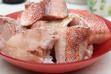 Close-up of portioned pieces of raw sea bass in a red plate.
