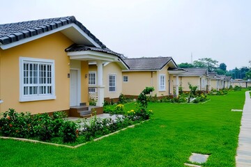 A row of small yellow houses in a row with green grass and flowers