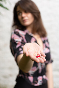 Young Woman Holding Two Red Strawberries in an Outstretched Hand