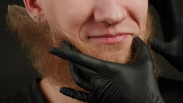 Make up artist making Disheveled blond beard for a man in theater with paint and glue, actors sfx cinema make up, close-up. Mens fashion, halloween style. making old guy.