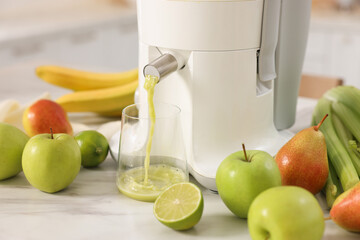 Modern juicer, fruits and glass on white marble table, closeup