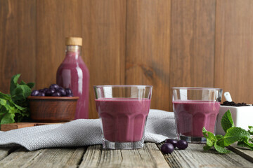Tasty fresh acai juice in glasses with berries and mint on wooden table