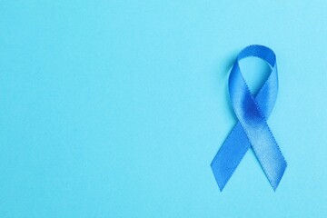 Blue ribbon on color background, top view with space for text. Prostate cancer awareness