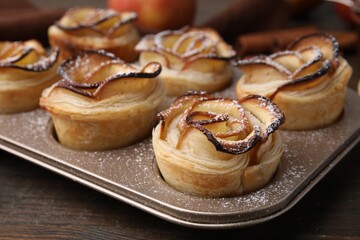 Freshly baked apple roses on wooden table, closeup. Puff pastry
