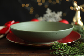Christmas setting. Plate, bowl and fir branches on wooden table, closeup