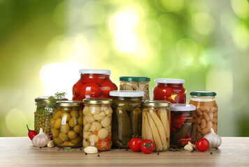 Jars with pickled vegetables and mushrooms on wooden table outdoors, space for text
