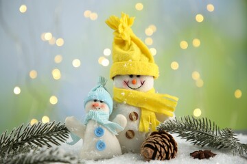 Cute decorative snowmen, fir branches and cone on artificial snow
