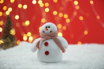 Cute decorative snowman on artificial snow against blurred lights