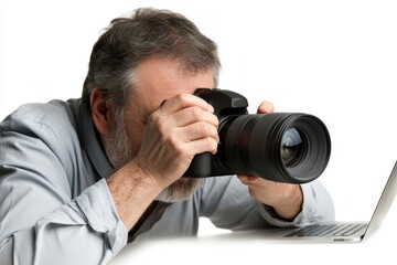 Photographer checking photos with DSLR camera with laptop nearby on white background.