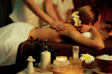 Aromatherapy massage ambiance or spa salon composition setup with focus decor candles and spa accessories on blur couple enjoying blissful aroma spa massage in resort or hotel background. Quiescent