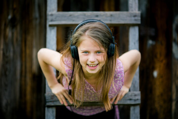 Fototapeta premium A playful portrait of a teenage girl wearing headphones, with a mischievous smile.