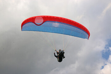 Tandem Paraglider flying in a cloudy sky	
