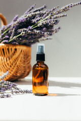 Natural cosmetics. Amber bottle with facial, bath liquid on a concrete background with lavender flowers. Front view