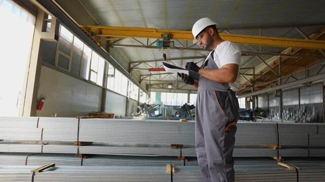 Indian warehouse worker writes out the invoice before sending metal profile