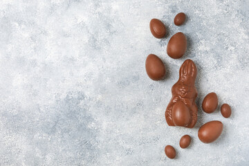 Easter chocolate egg on textured background. Easter celebration concept. Easter chocolate rabbit. Chocolate sweet eggs. Candies on textured wooden table. Space for text.Copy space. Gift. Banner.